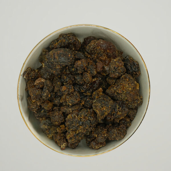 Top view of Guggul, also known as Myrrh of India, in a bowl. The dark, coarse resin pieces are irregularly shaped and have a deep brown to almost black color.